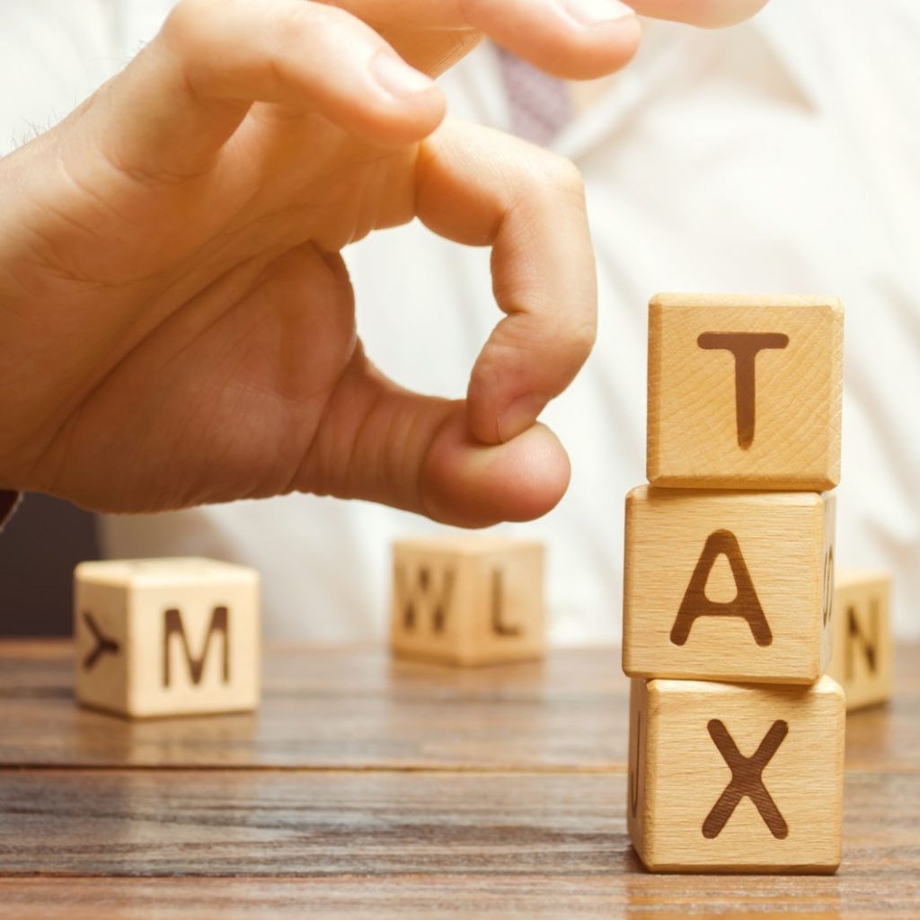 A man flicking blocks that spell out TAX - Tax planning